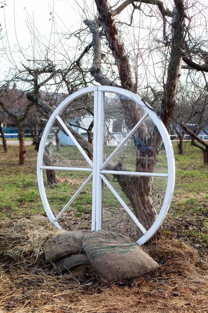 Grande roue en bois avec des sacs et du foin à côté des arbres dans le jardin