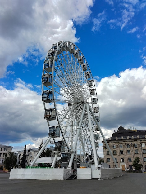 Grande roue de Ferris sur le fond du ciel bleu avec des nuages et des bâtiments