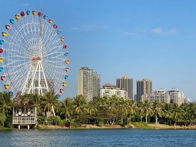 Photo la grande roue par les bâtiments contre le ciel en ville