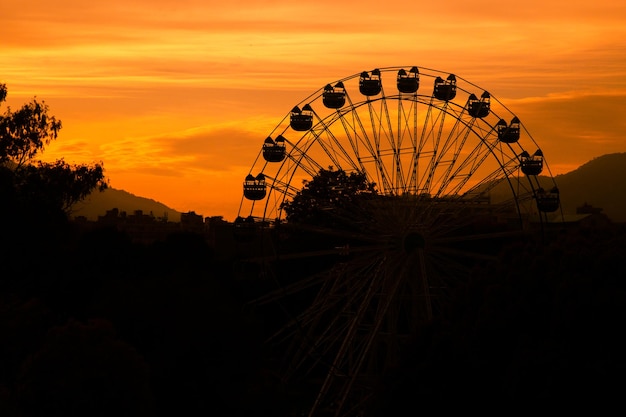 Une grande roue se découpe sur un ciel au coucher du soleil.