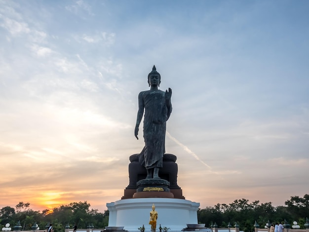 Grande statue de Bouddha marchant la statue principale du diocèse bouddhiste sous le ciel crépusculaire en Thaïlande