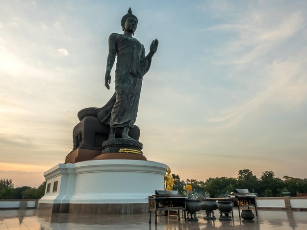 Grande statue de Bouddha marchant la statue principale du diocèse bouddhiste sous le ciel crépusculaire en Thaïlande