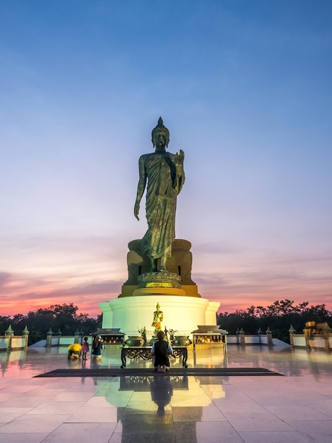 Grande statue de Bouddha marchant la statue principale du diocèse bouddhiste sous le ciel crépusculaire en Thaïlande