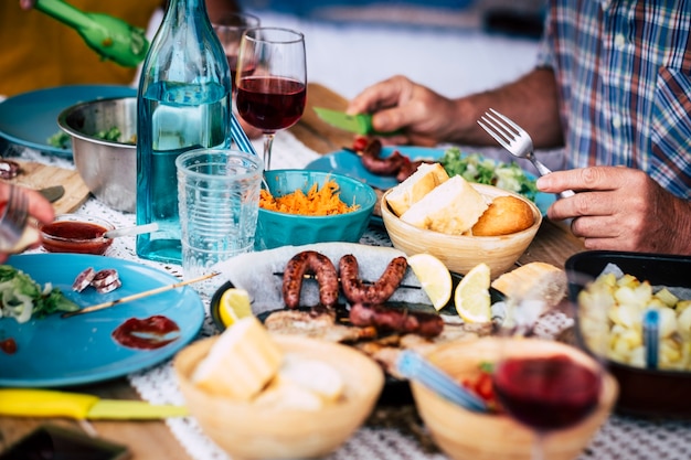 Grande table pleine de vie alimentaire pain, viande, légumes ... - certaines personnes assises à côté de la table mangeant et buvant de la vigne et de l'eau - célébration - beaucoup de salade et tous les types de nourriture