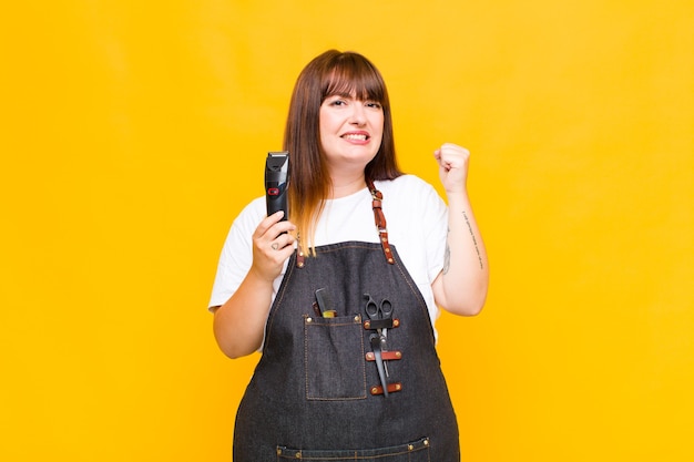 Grande taille femme criant agressivement avec une expression de colère ou avec les poings fermés célébrant le succès