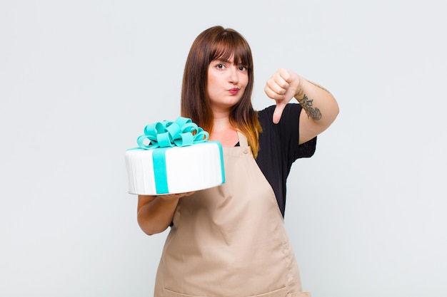 Grande taille femme se sentant en colère, en colère, agacée, déçue ou mécontente, montrant les pouces vers le bas avec un regard sérieux