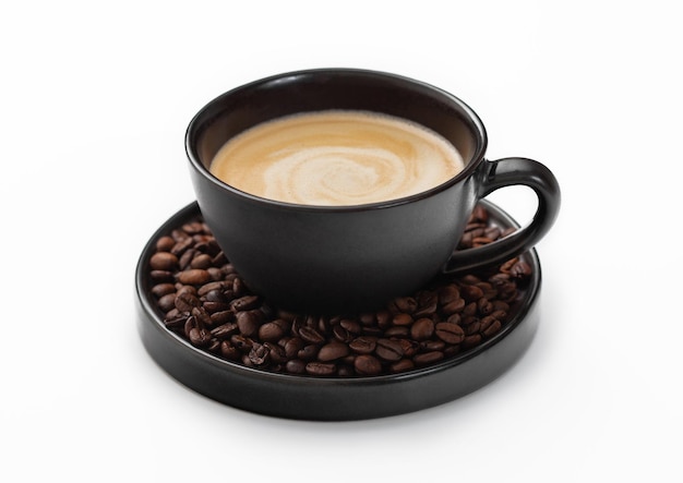 Une grande tasse de porcelaine de café noir crémeux chaud et de haricots crus frais sur une soucoupe sur fond blanc