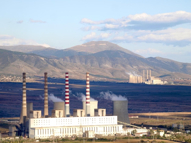 Une grande usine avec des cheminées et des montagnes en arrière-plan