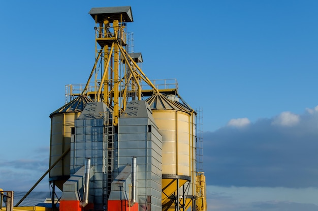 Une grande usine moderne pour le stockage et la transformation des céréales Vue du grenier par une journée ensoleillée Grands barils de céréales en fer contre le ciel Fin de la saison des récoltes