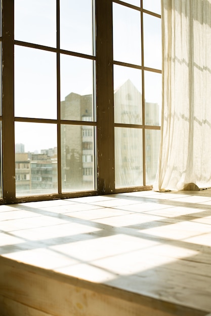 Grande vieille fenêtre en bois avec rideau transparent à la lumière du soleil