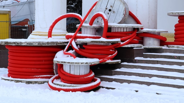 Grandes bobines de tuyau ondulé flexible rouge utilisé pour protéger les câbles dans les installations électriques. Beaucoup de tuyaux en plastique polyéthylène colorés utilisés dans la construction de systèmes de plomberie.