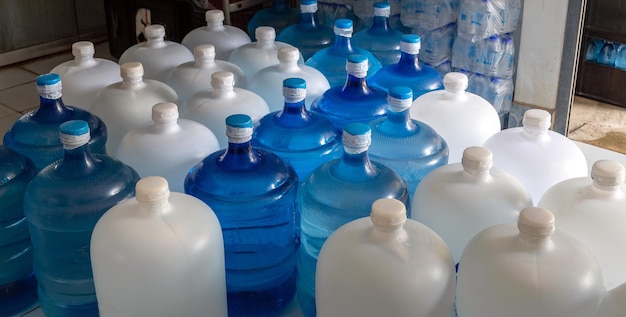 Grandes bouteilles en plastique ou gallons blancs et bleus d'eau potable purifiée à l'intérieur de la production