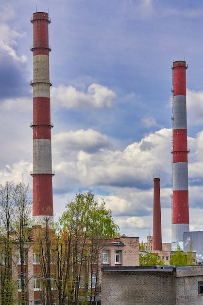 Grandes cheminées d'usine sur fond de ciel nuageux et de bâtiments résidentiels