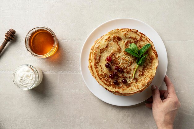 De grandes crêpes sur fond de pierre claire sont servies par une cuisinière vue de dessus cuisine maison Pâques