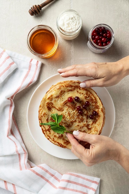 De grandes crêpes sur fond de pierre claire sont servies par une cuisinière vue de dessus cuisine maison Pâques