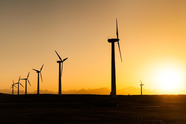 Grandes éoliennes dans le désert au coucher du soleil