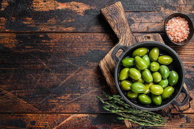 Grandes olives vertes dans un bol avec du thym.