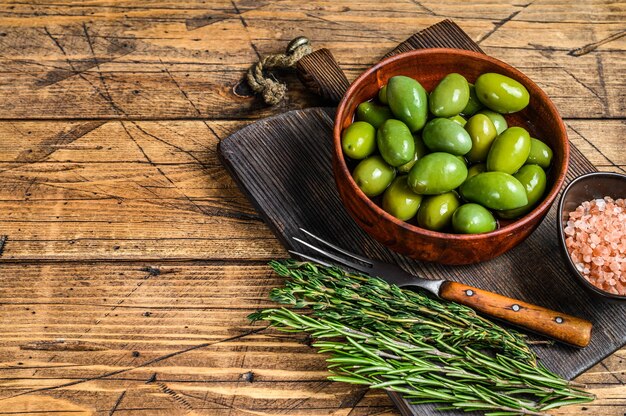 Grandes olives vertes marinées dans un bol en bois avec de l'huile