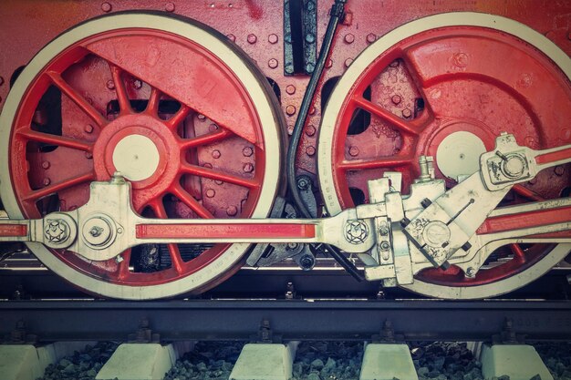 Grandes roues un gros plan de la locomotive vintage avec le moteur à vapeur sur les voies ferrées de couleur rouge