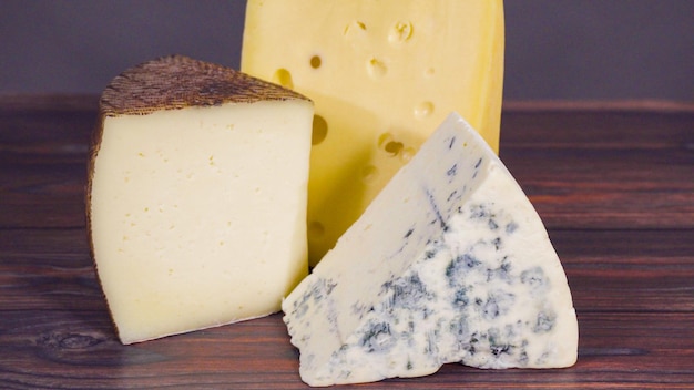 Grandes tranches de fromage gastronomique sur fond de bois rustique.