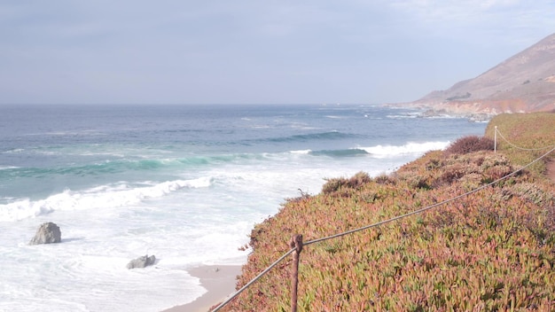 De grandes vagues de l'océan pacifique se brisent sur la plage vide de la côte californienne et de la montagne