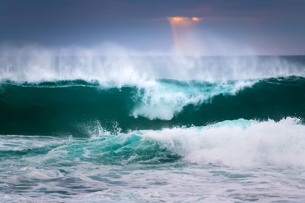 De grandes vagues sur la plage au coucher du soleil de l'océan Atlantique à Nazaré au Portugal