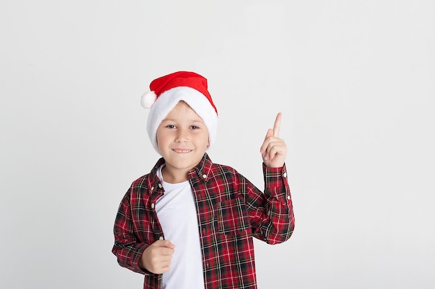 Grandhomme dans un chapeau de père noël montre la classe avec son pouce les émotions des enfants portrait d'un enfant sur fond blanc