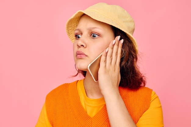 Grandhomme dans un pull orange en chapeau jaune parlant au téléphone fond rose inchangé