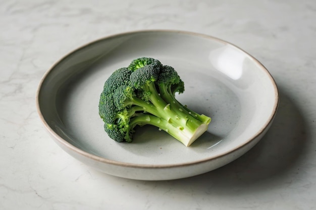 De grands brocolis verts se trouvent sur une assiette blanche vide sur une table en marbre couleurs claires alimentation saine