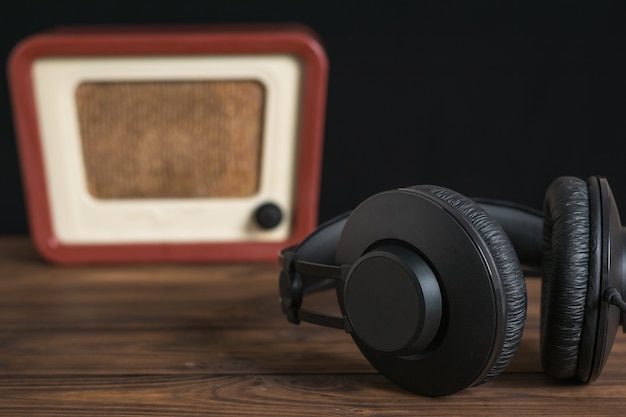 Photo grands écouteurs noirs sur le fond d'une radio rétro. technique de reproduction sonore et vidéo.