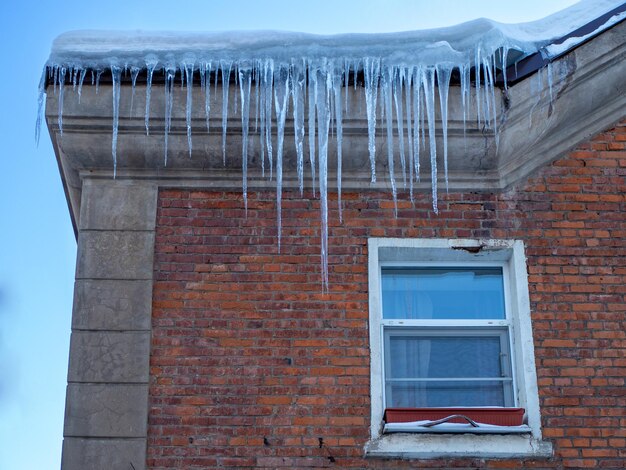 Grands glaçons d'hiver suspendus au toit de la maison