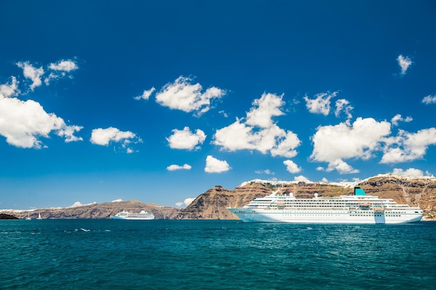 Photo grands paquebots de croisière près des îles grecques. mer turquoise lumineuse et ciel bleu. l'île de santorin, grèce