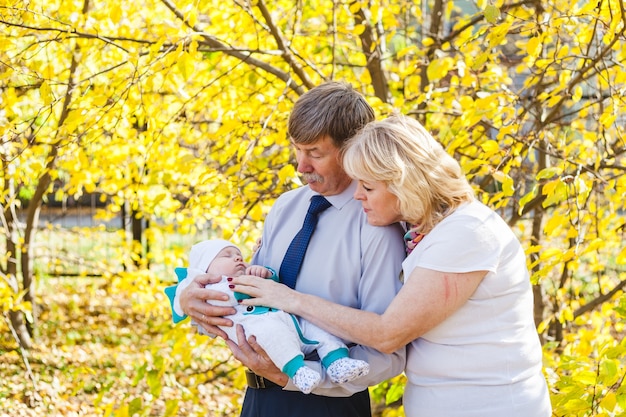 Grands-parents avec un bébé, un petit garçon marchant à l'automne dans le parc ou la forêt. Feuilles jaunes, la beauté de la nature. Communication entre un enfant et un parent.