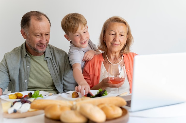 Grands-parents montrant quelque chose sur leur ordinateur portable à leur petit-fils