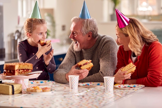 Grands-parents avec petite-fille célébrant ensemble le gâteau d'anniversaire à la maison