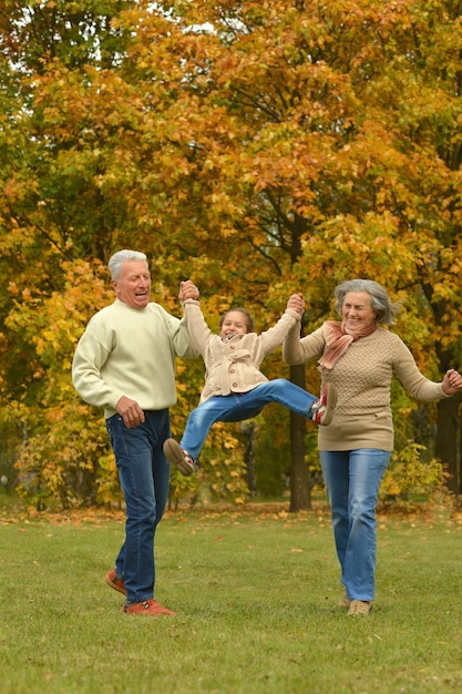 Grands-parents avec petite-fille s'amusant dans le parc en automne