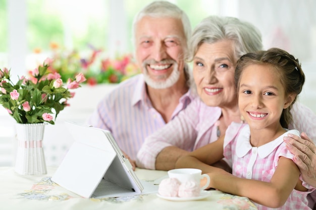 Grands-parents avec sa petite-fille utilisant une tablette à la maison