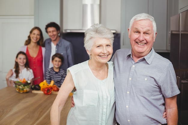 Grands-parents souriants avec la famille dans la cuisine