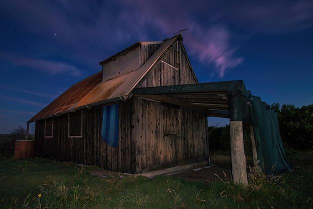 Une grange sur le terrain la nuit avec la lune dans le ciel