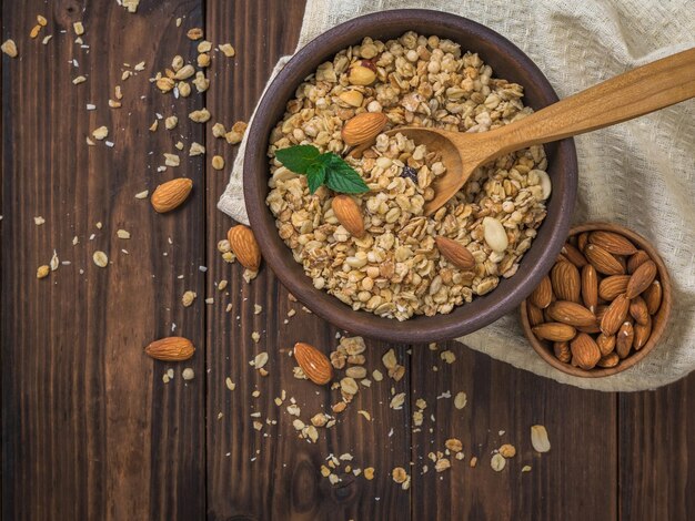 Granola et amandes dans un bol en argile sur une table en bois