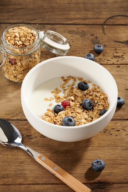 Granola au yaourt et aux baies dans un bol blanc sur une table en bois