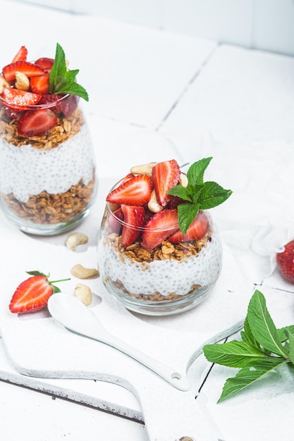 Granola au yaourt chia et fraises dans un verre sur fond blanc