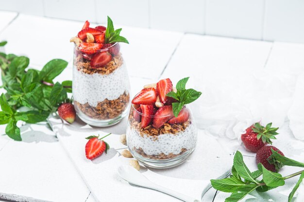 Granola au yaourt chia et fraises dans un verre sur fond blanc