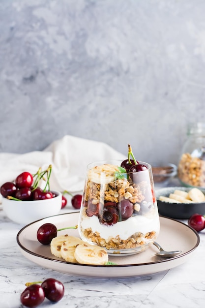 Granola au yogourt banane cerise et graines de lin dans un verre sur la table Vue verticale