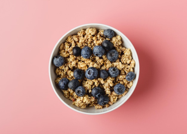 Granola aux bleuets dans un bol sur fond rose