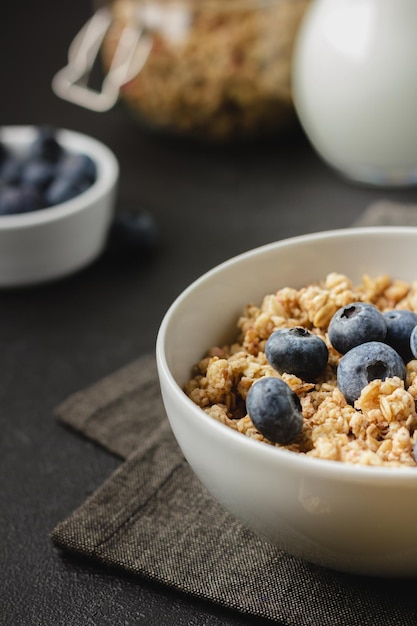 Granola aux bleuets dans un bol sur une serviette sombre