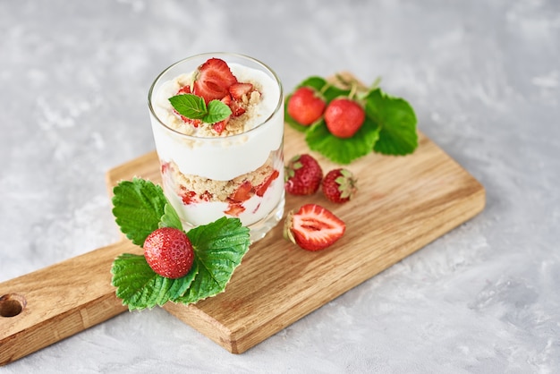 Granola aux fraises ou smoothie dans le verre et les baies fraîches sur une planche à découper, vue de dessus. Petit-déjeuner sain