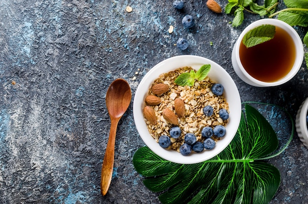 Granola aux myrtilles dans une assiette blanche et tasse de thé pour le petit déjeuner