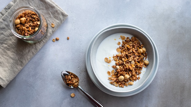 Granola aux noix et au yaourt naturel dans un bol. Concept de nutrition saine et biologique. surface en béton gris.