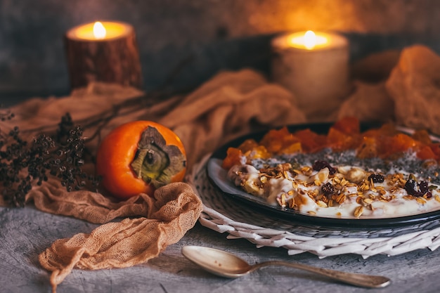 Granola à l'avoine avec yogourt, fruits secs, graines, miel, kaki dans un bol